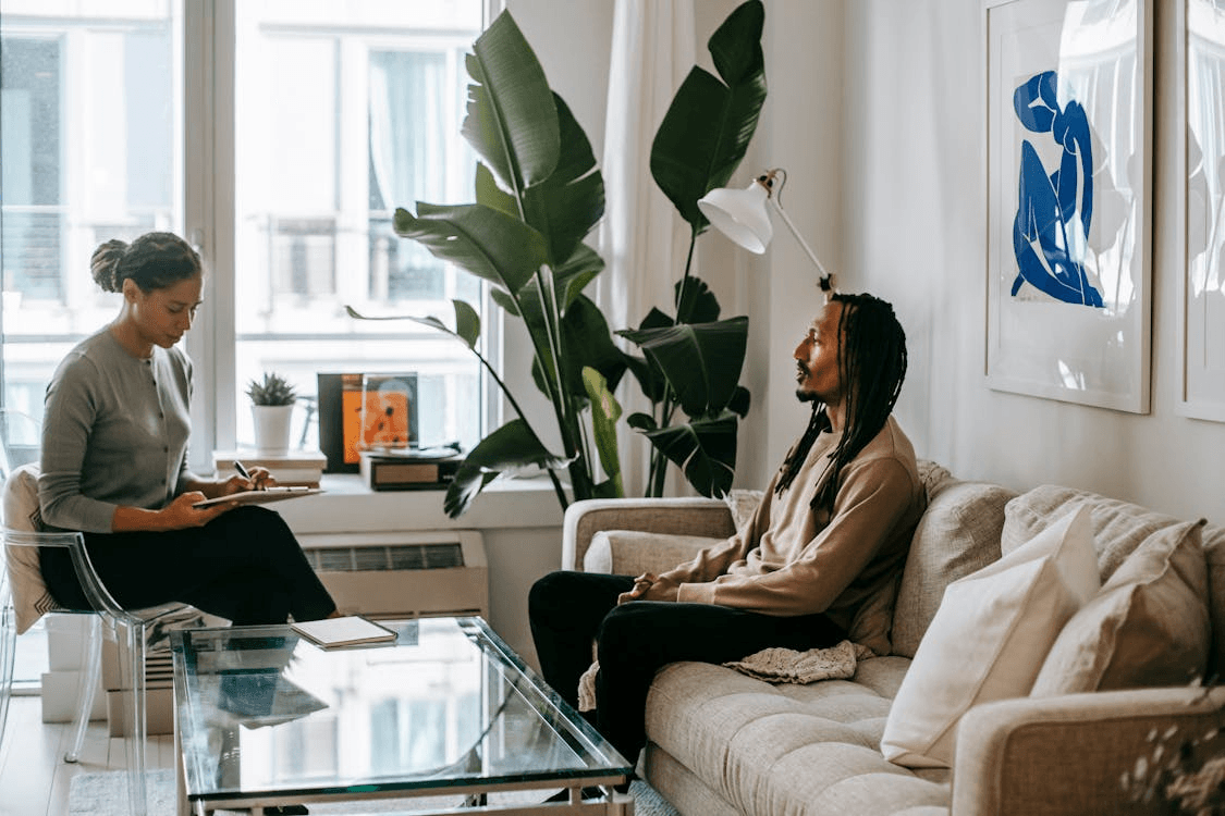 Two therapists in a bright living room consulting on session notes